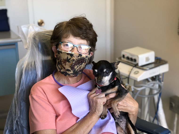 A dental patient in a mask holds Kismet.