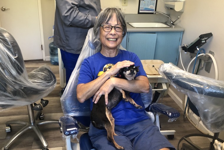 Dental patient smiles while holding Kismet, a dental therapy dog.