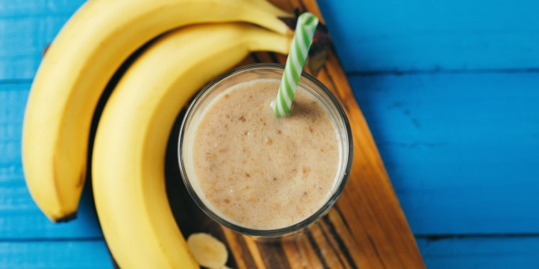 Milk smoothie with banana on wooden blue table