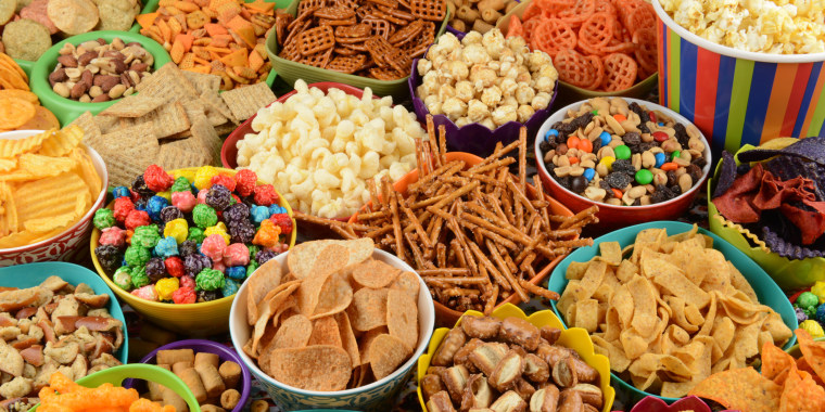 Full frame collage / variety of snacks in bowls; pretzels, popcorn, corn chips, crackers, peanuts, potato chips