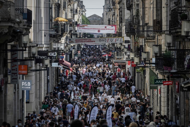 Image: Pedestrians, some of them wearing protective face masks due to the COVID-19 coronavirus pandemic, walk along a street lined with shops in Bordeaux, southwestern France