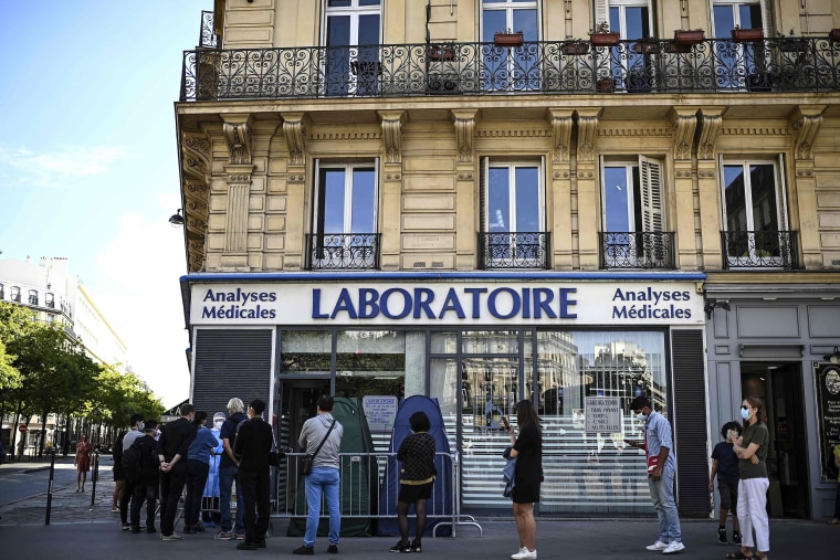 Image: People stand in line as they wait for a COVID-19 test in Paris.
