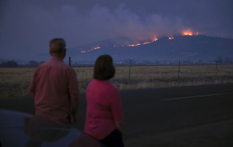 Image: Local residents look at smoke and fire over a hill during wildfires near the town of Medford, OR, Sept. 9, 2020.