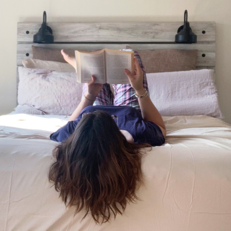 Woman reading in bed with white sheets