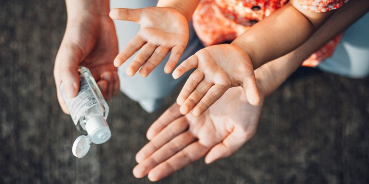 adult applying hand sanitizer to childs hands