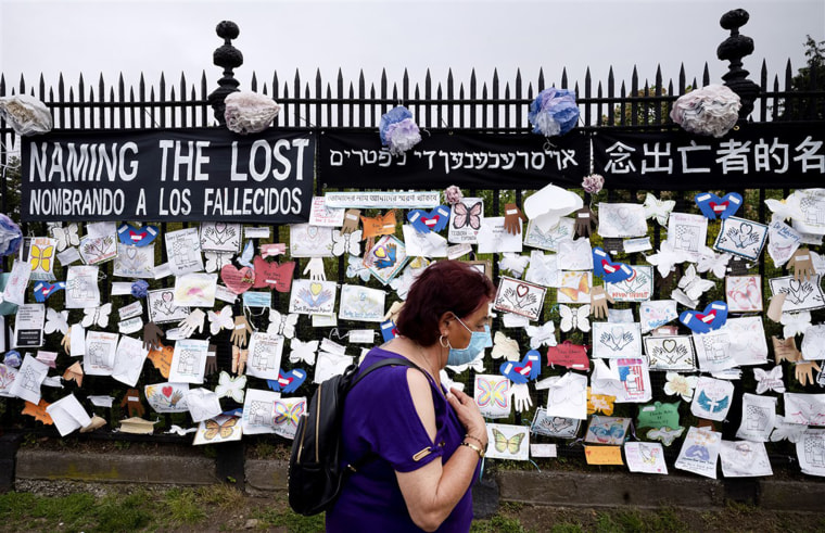 A woman passes a fence outside Green-Wood Cemetery, adorned with tributes to victims of Covid-19, in Brooklyn, N.Y., on May 28. The memorial is part of the Naming the Lost project, which seeks to humanize victims who are often simply listed as statistics.