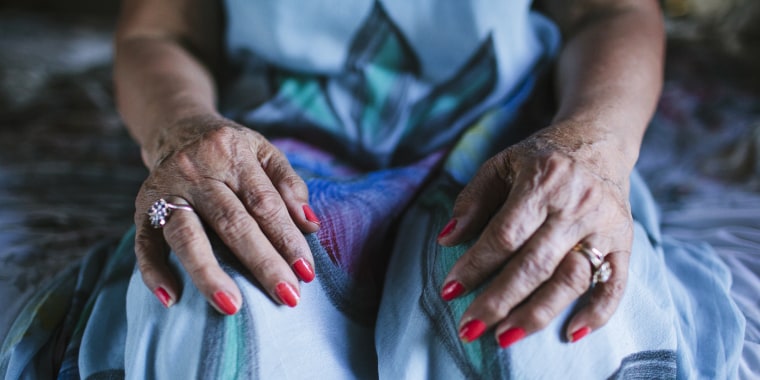 Close up of hands of older woman resting on knees