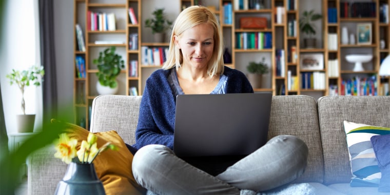 woman sitting in living room using laptop