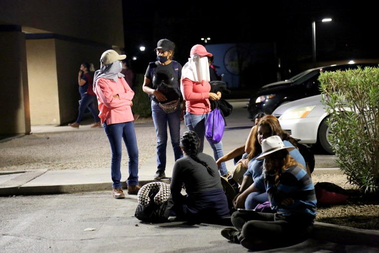 Migrant and seasonal day laborers gather outside a Chase parking lot to wait for buses that will take them to work on agricultural fields several miles away.