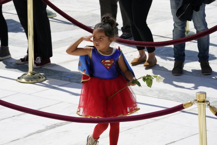Image: A child in a Supergirl costume pays respects as Justice Ruth Bader Ginsburg lies in repose under the Portico at the top of the front steps of the U.S. Supreme Court building, in Washington