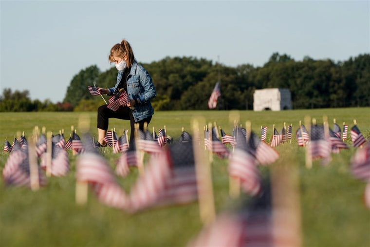 A volunteer places American flags representing some of the 200,000 lives lost in the United States in the coronavirus pandemic on the National Mall in Washington, on Sept. 22.