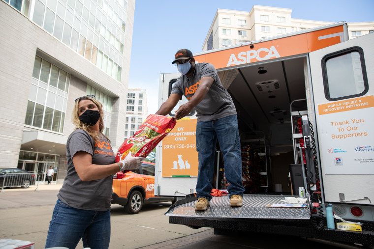 Volunteers pass pet food for a pantry.