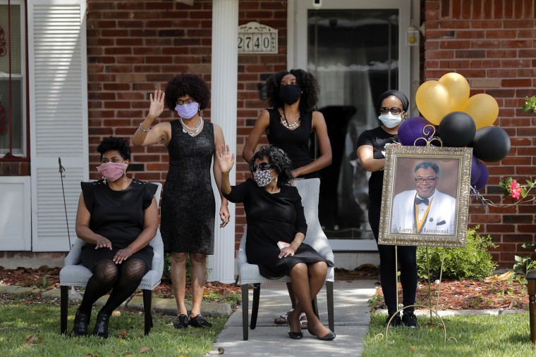 Image: The family of Larry Hammond wave as a line of cars with friends and family, who could not attend his funeral due to the coronavirus, pass by their home, in New Orlea