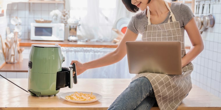 woman sitting on kitchen counter using air fryer