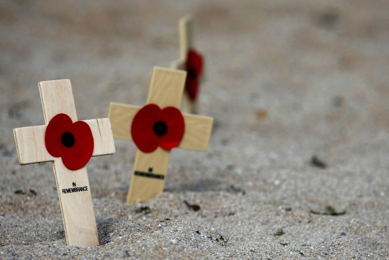 Wooden crosses with poppies are left in