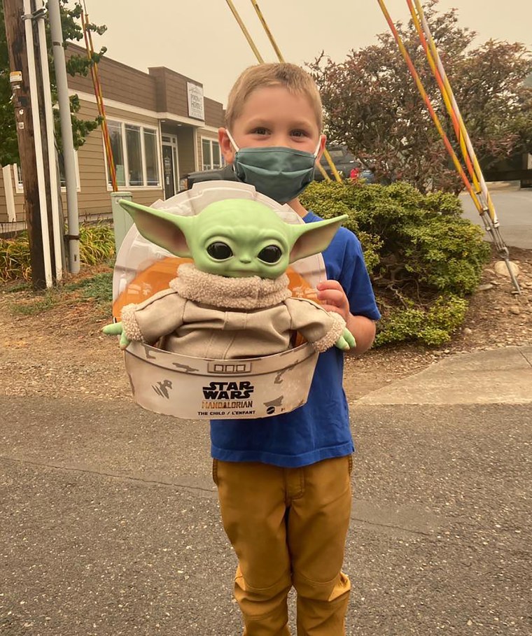 Five-year-old Carver holds up a Baby Yoda toy in Scappoose, Oregon. Carver donated the toy to Oregon firefighters, who have been having fun posing the tiny green Force user on the fire lines since. (Courtesy of Tyler Eubanks)