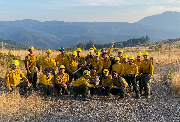 The Oregon Air National Guard pose for a group shot with Baby Yoda on Sept. 20, 2020 while fighting the Holiday Farm Fire in Blue River, Oregon. (Courtesy of Jaebyn Drake via AP)