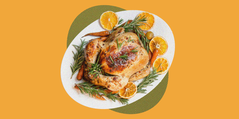 Traditional Christmas roasted chicken garnish orange, carrot, and rosemary on light table. Top view. Copy space.