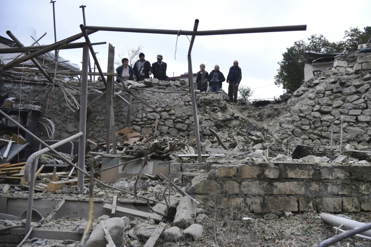 Image: Men look at the damage in a residential area after shelling by Azerbaijan's artillery during a military conflict in self-proclaimed Republic of Nagorno-Karabakh, Stepanakert