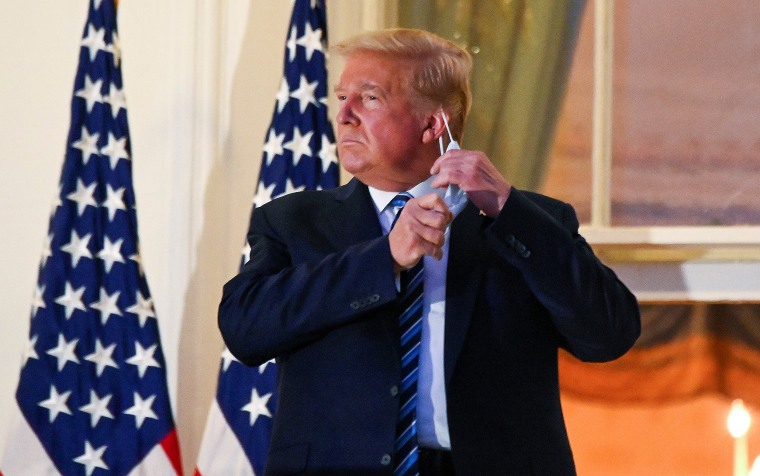Image: U.S. President Donald Trump pulls off his face mask as he returns to the White House after being hospitalized at Walter Reed Medical Center for coronavirus disease (COVID-19), in Washington