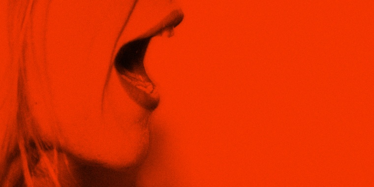 Image: A woman screams in rage on a bright red background