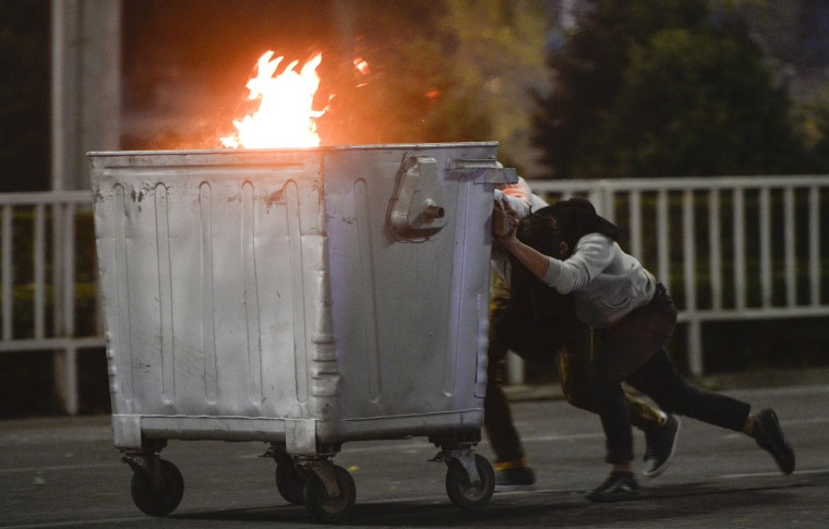 Image: Protesters push a burning trash can towards riot police during a rally against the results of a parliamentary vote in Bishkek, Kyrgyzstan