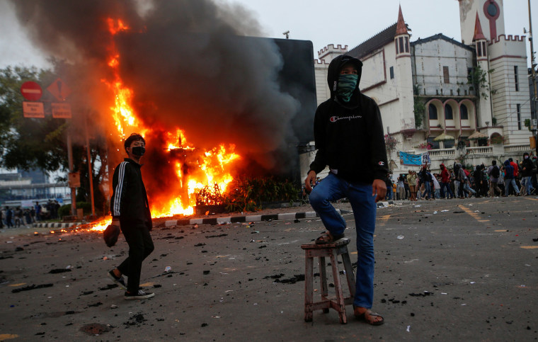 Image: Demonstrators are seen next to a burning police station in Jakarta 