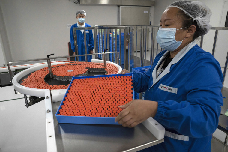Image: A worker feeds vials for production of SARS CoV-2 Vaccine for COVID-19 at the SinoVac vaccine factory in Beijing