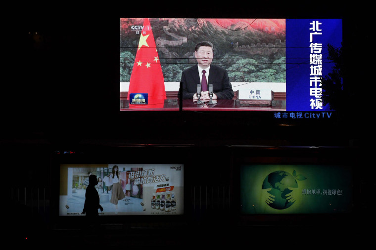 Image: An image of Chinese President Xi Jinping appearing by video link at the United Nations 75th anniversary is seen on an outdoor screen as a pedestrian walks past below in Beijing.