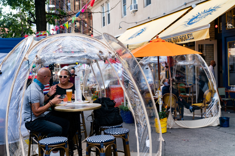 People sit outside Cafe Du Soleil under bubble tents