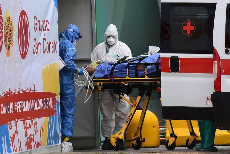 Image: Medical workers stretch a patient from an Italian Red Cross ambulance into an intensive care unit set up in a sports center outside the San Raffaele hospital in Milan, during the COVID-19 new coronavirus pandemic.