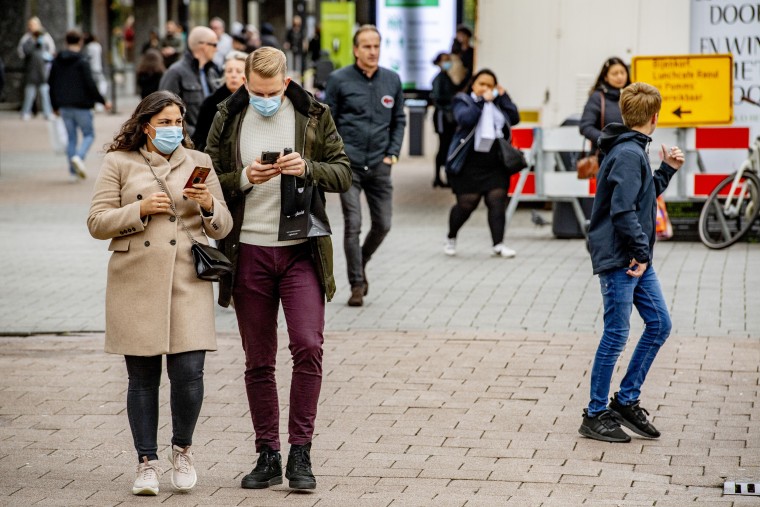 People wearing face masks as a preventive measure walk on