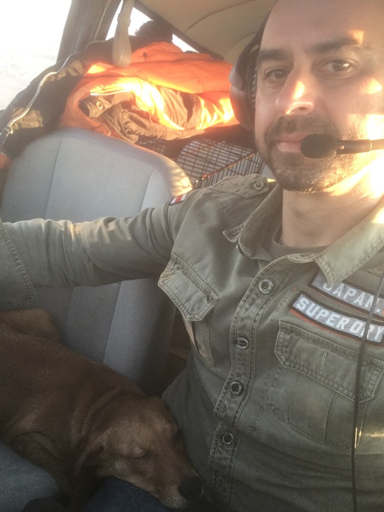 A dog relaxes in Eduard Seitan's lap while he flies a plane.