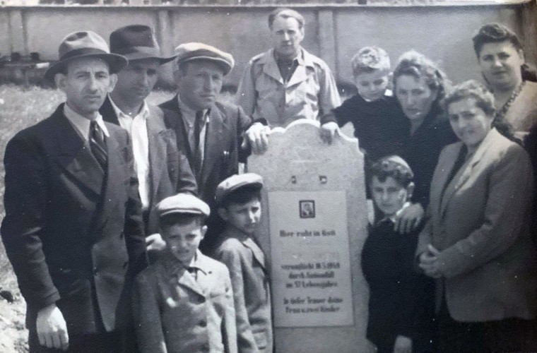 The Eisenberg and Brandspiegel families gather around the tombstone of Abraham Eisenberg at the Hallein Displaced Persons Camp in Austria in June 1948.