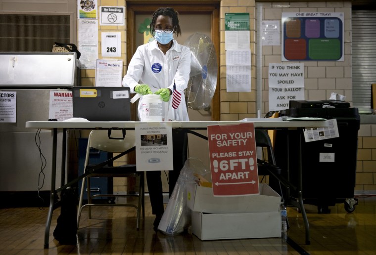 Debra Moore sanitizes her workspace during primary Election Day on Aug. 4, 2020, in Detroit.
