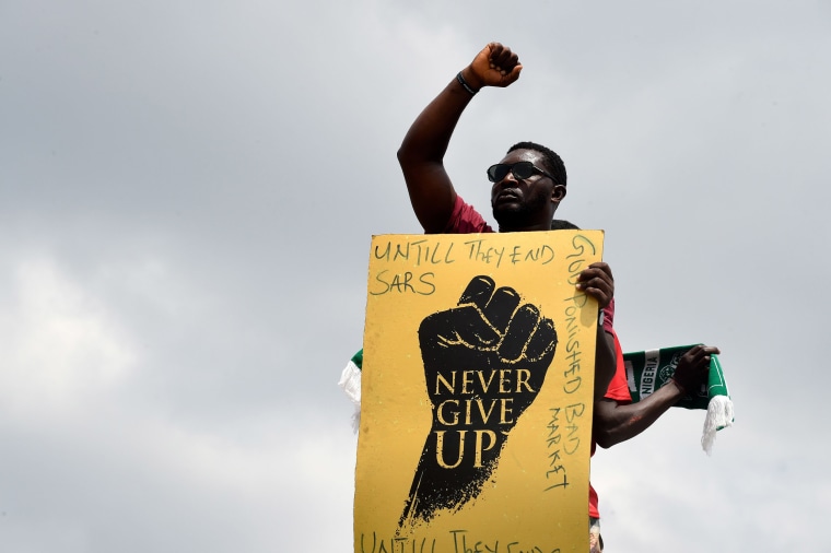 Image: A protester raises his fist and holds a placard during a demonstration to protest against police brutality at Magboro, Ogun State in southwest Nigeria