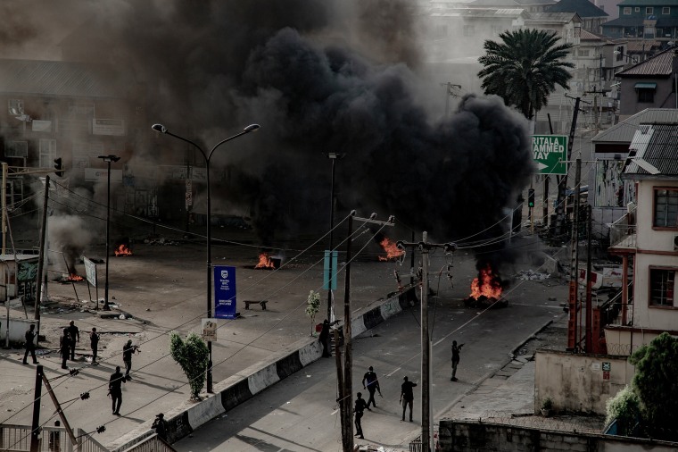 Image: Armed men are seen near burning tires on the street, in Lagos