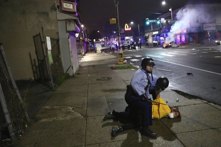 Image: Police handcuff a protester after charging at a crowd in West Philadelphia early Tuesday.