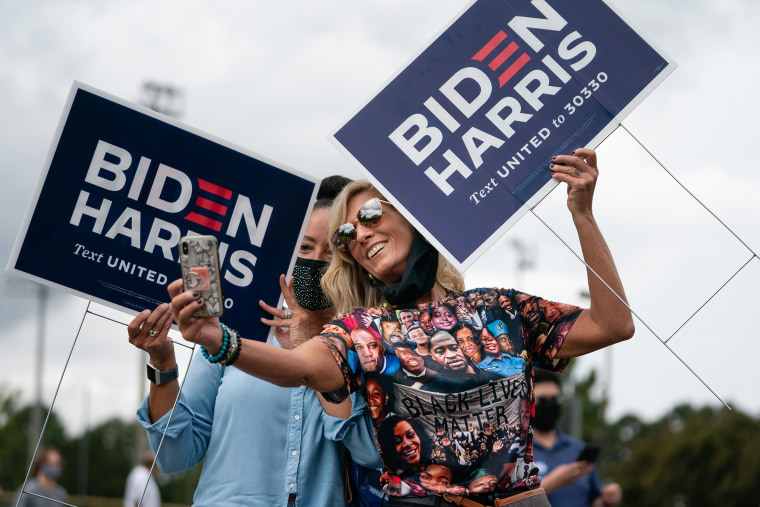 Image: Two women holding Biden/Harris lawns signs take a selfie at a rally with Democratic Senate candidates Rev. Raphael Warnock and Jon Ossoff on Oct. 24, 2020, in Duluth, Georgia.