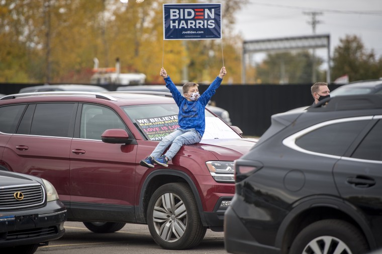 A boy holds a sign while waiting for the arrival of Sen. Kamala Harris on Oct. 25, 2020 in Pontiac, Mich.