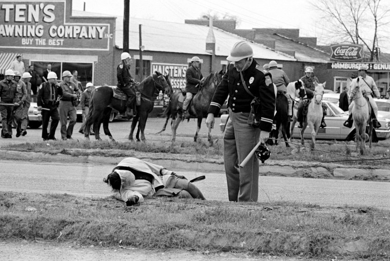 Image: An officer approaches an unconscious woman as mounted police officers chase marchers in Selma, Ala., during a voting rights march to Montgomery in 1965.