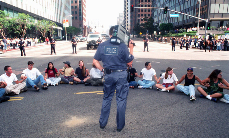 A Los Angeles Police Department official videotapes a rally to protest the University of California regents' decision to scrap affirmative action policies, on Oct. 12, 1995, in Los Angeles.