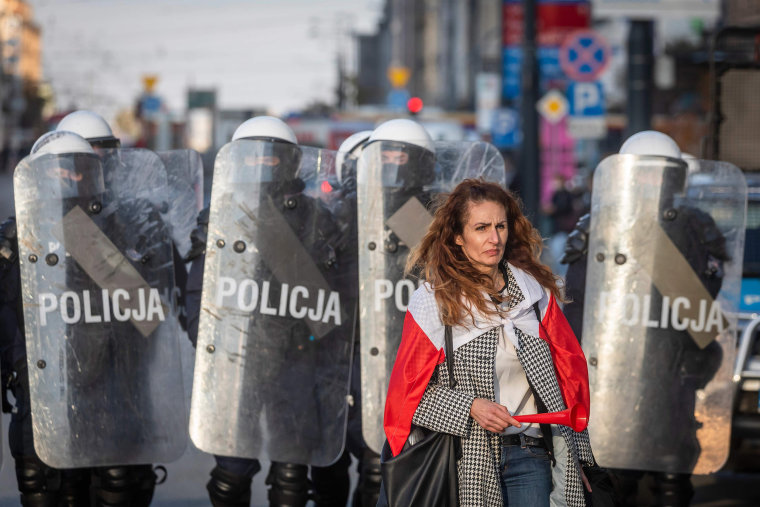 Image: A woman stands in front of Police during a demonstration against the coronavirus restrictions on Oct. 24, 2020 in Warsaw, amid the coronavirus Covid-19 pandemic.