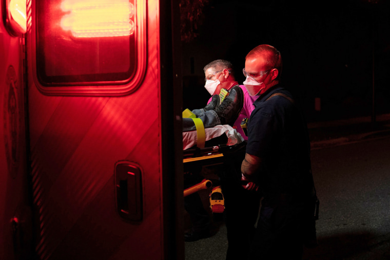 Firefighters and paramedics with Anne Arundel County Fire Department wear enhanced protective equipment as they load a patient into an ambulance on Oct. 26, 2020 in Glen Burnie, Md.