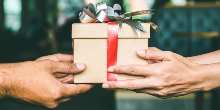 Cropped Hand Of Man Giving Christmas Present To Female Friend