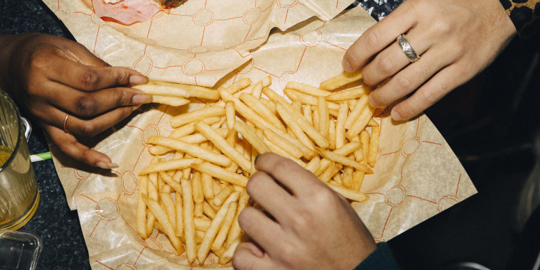 High angle view of friends eating burger and french fries at table in cafe