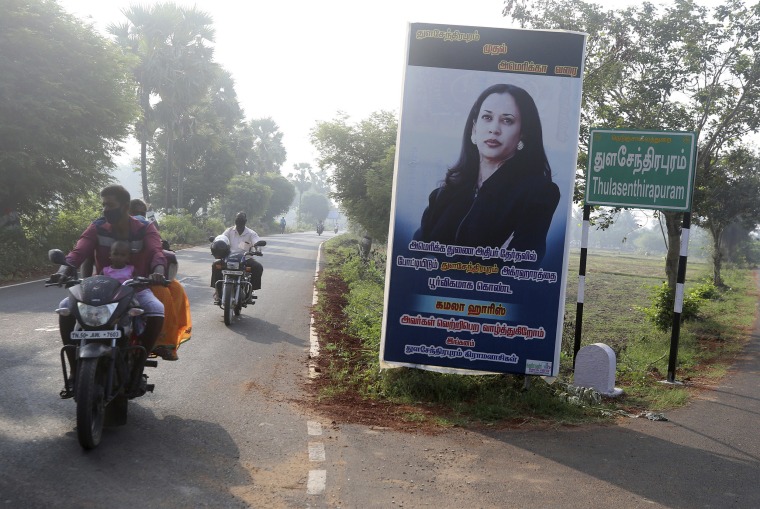 Image: People ride past a billboard featuring Sen. Kamala Harris in her ancestral village, Thulasendrapuram.
