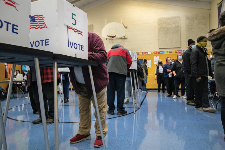 Voters fill out their ballots at a school gymnasium on Election Day in Lansing, Mich.