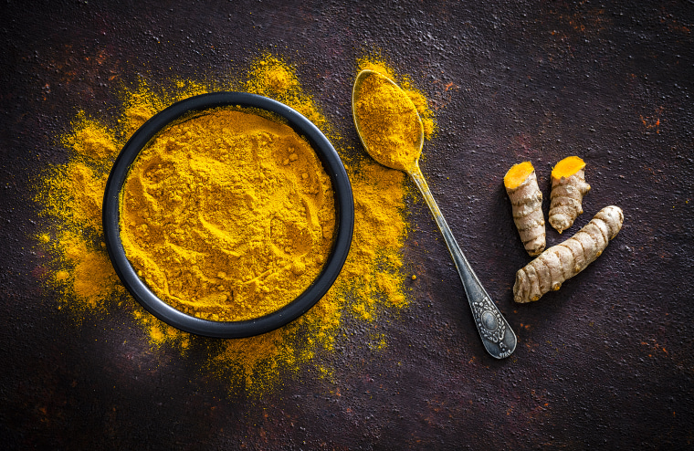 Spices: Turmeric roots and powder shot from above