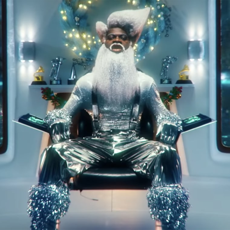 Lil Nas X rocks a shiny, silver outfit as a futuristic Santa, instead of the character's traditional red suit.